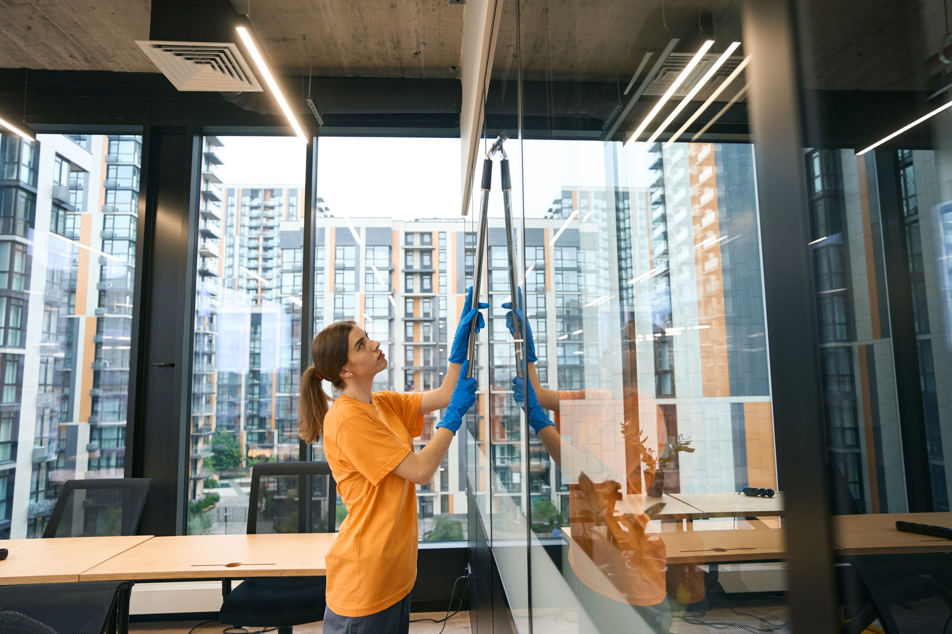 Cleaning service employee uses special glass scraper with long handle